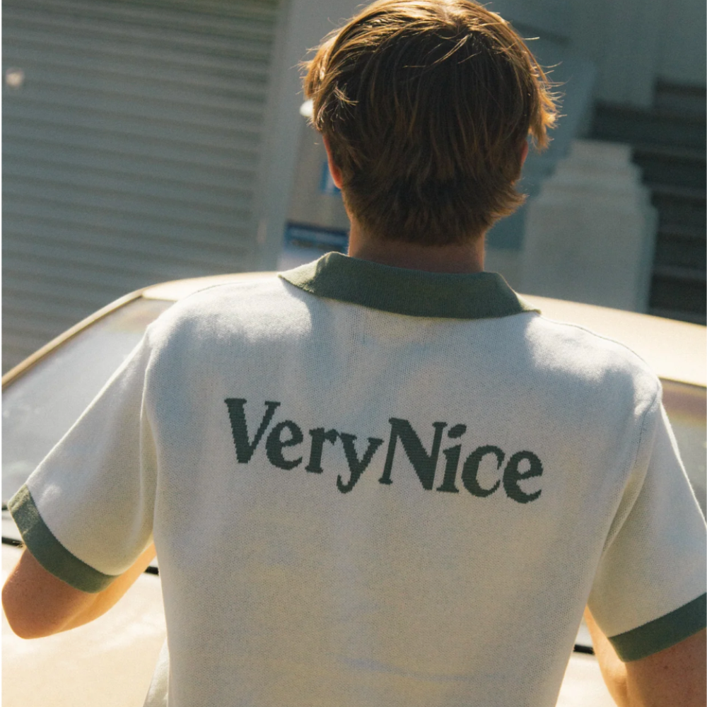 Person wearing a white polo shirt with 'VeryNice' text on the back, standing outdoors.